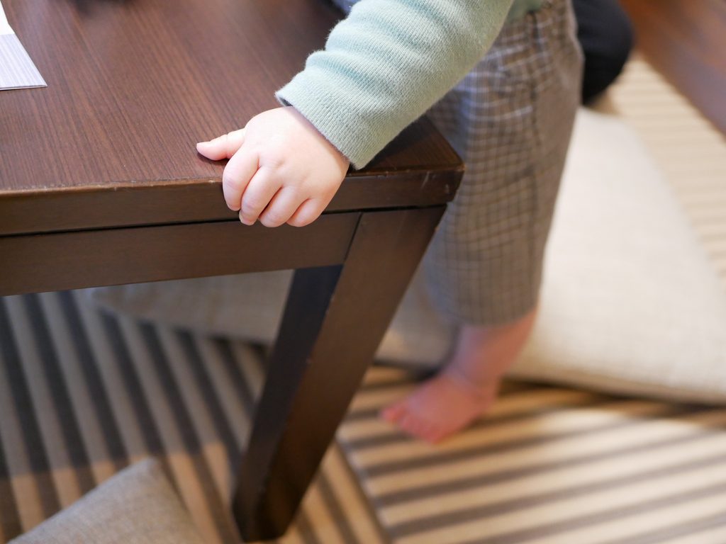 テーブルにつかまり立ちをする11か月の子ども